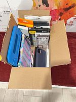 Top view of box showing assorted packaged and loose cellphone accessories
