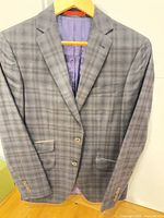 Full view of plaid sports jacket on hanger showing front, lapels and pockets