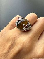 Ring worn on hand showing tiger’s eye stone and enamel flowers