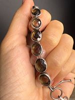 Bracelet held in hand showing six smoky quartz stones in sterling bezels