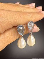 Front view of earrings showing pear-shaped faceted blue topaz tops and white pearl drops