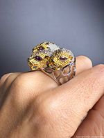 Angled view of ring on hand showing two gold-accented panther heads with pink tourmaline eyes and silver shank