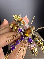 Close-up of dragonfly brooch showing multicolor gemstones and gold overlay