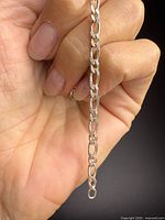 Chain held in hand showing Figaro link pattern