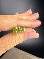 Earrings held in hand showing peridot stones and prong settings