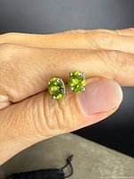 Close-up of peridot stud earrings on hand showing gemstone color and prong setting