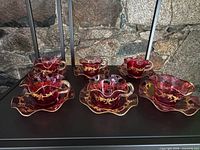 Full set of six cranberry glass teacups and saucers displayed