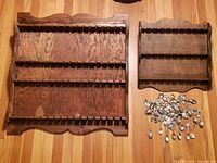 Two wooden spoon racks and pile of souvenir spoons on floor