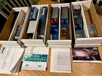 Four long card boxes holding assorted Star Wars CCG cards, checklist sheets and empty booster wrappers