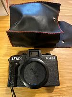 Front of Akira TC-002 camera with body cap and slip case behind