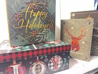 Front view of all four Christmas paperboard boxes and bags