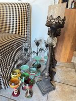 Group view showing three metal pedestal candleholders, candelabrum and colored goblets