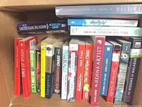 Box of assorted paperback books showing spines and several identifiable titles