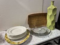 Group view of plates, glass plates, wicker tray, vase