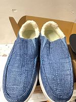 Top view of blue slip-on shoes showing woven upper and shearling lining