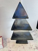 Front view of three-tier metal tree-shaped tray showing overall form and patina