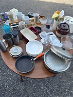Overall view of assorted cookware, tableware, utensils, small appliances on round table