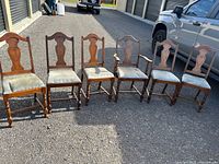 Six wooden dining chairs lined up outdoors showing overall style and quantity