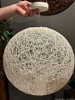 Full view of spherical woven pendant light held by canopy