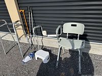 Full lot overview showing shower chair, walker, canes, toilet safety rails, bath stool, sock aid