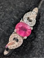 Top view showing ruby CZ centre stone and pavé CZ side scrolls on silver band