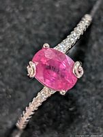 Top view of silver ring showing oval pink center stone and shoulder accents