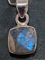 Front view of silver pendant with blue flashing labradorite