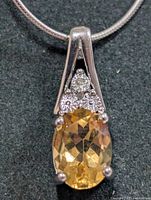 close-up of pendant showing citrine, diamond, prongs and bail
