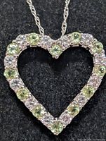 Close-up of pendant showing peridot and clear stones in heart shape