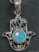 Front view of silver hamsa pendant showing opalite cabochon and filigree detail