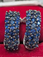 front view of sapphire-set silver hoop earrings in box