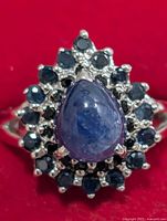 Front view of silver ring showing pear cabochon sapphire and surrounding round sapphires