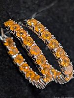 Front view of both silver hoops showing orange sapphire settings