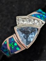 Front view showing blue triangular topaz, clear accent stones, opalite inlays