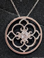 Front of pendant showing scroll design and central cubic zirconia