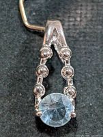 Front view of silver pendant with round blue topaz stone