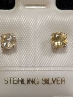 Front view of citrine stud earrings in packaging, sterling silver text visible