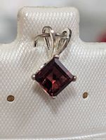 front view of sterling silver pendant showcasing square garnet stone