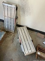 Both aluminum work stands folded and one opened flat on floor