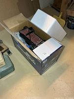 Sander inside original box with foam inserts and power cord visible