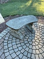 Full view of curved concrete bench on stone patio