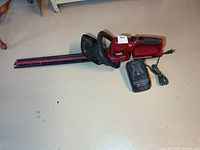 Hedge trimmer with battery installed and charger beside it
