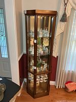 Full view of curio cabinet showing wood frame, glass panels, mirrored back, shelves