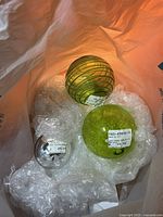 Bag with three glass balls: two large green, one small silver