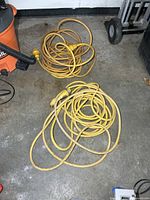 Two coiled yellow marine extension cords on floor