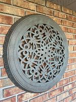 Front view of round scrollwork wall medallion mounted on brick exterior