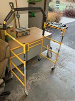 Full view of yellow scaffold frame with casters and padded top bar