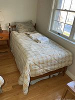 Complete bed setup with quilt, mattress, boxspring and side table visible