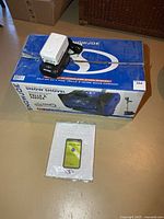 Top view of boxed Snow Joe snow shovel with battery, charger and manual visible