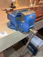 Side view of blue Woden bench vise mounted on bench